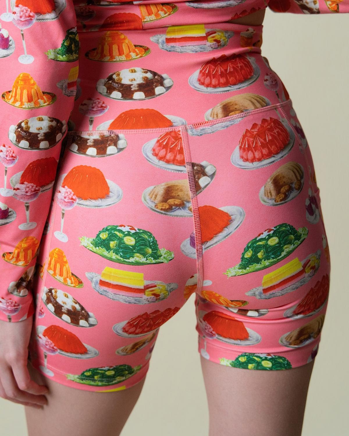 Person wearing pink shorts with dessert pattern on a plain background