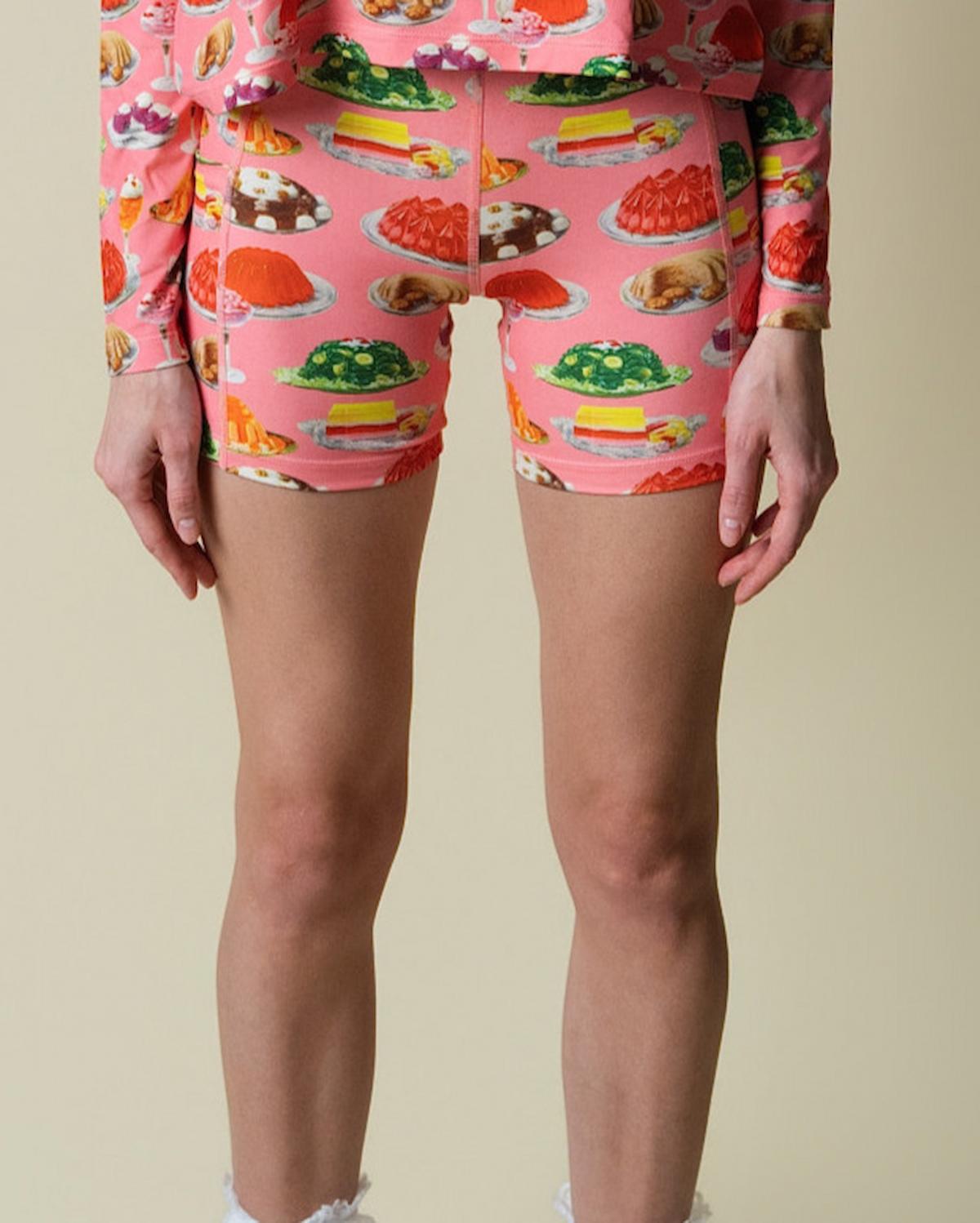 Person wearing pink shorts with dessert pattern on a beige background