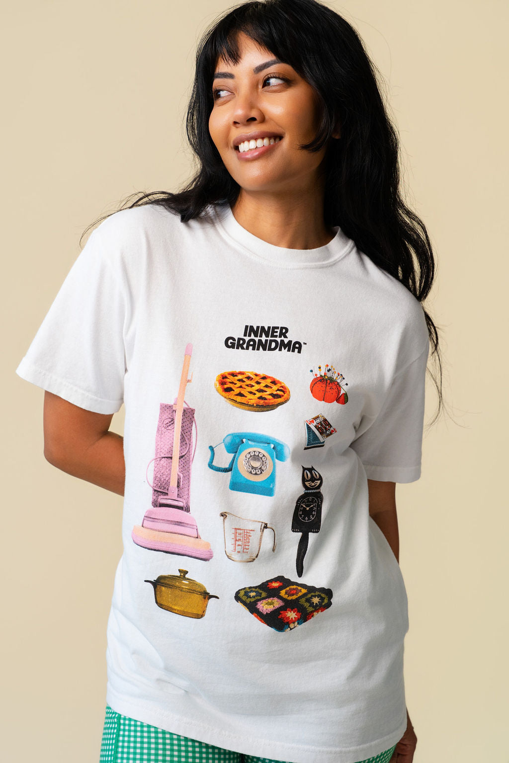 Person wearing a white t-shirt with colorful graphics of grandma's items on a beige background.