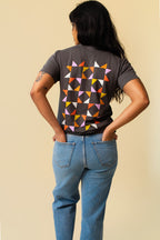 Back of person wearing a gray shirt with colorful quilted pattern.