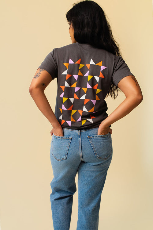 Back of person wearing a gray shirt with colorful quilted pattern.