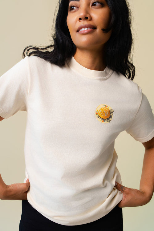 Person wearing a beige t-shirt with a small graphic of sour dough bread.
