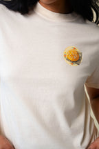 Close up of a person wearing a beige t-shirt with a small graphic of sour dough bread.