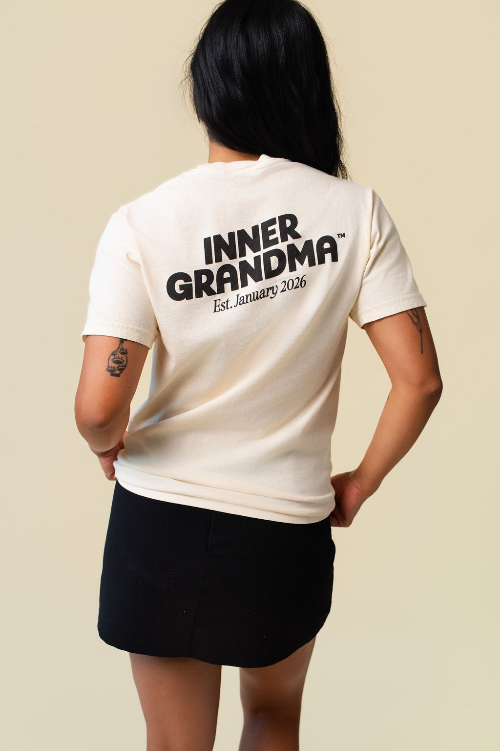 Back of person wearing a beige t-shirt with 'inner grandma' printed on the back.