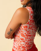 Side of person wearing a tank top with orange vintage-style food coupon pattern and jeans.
