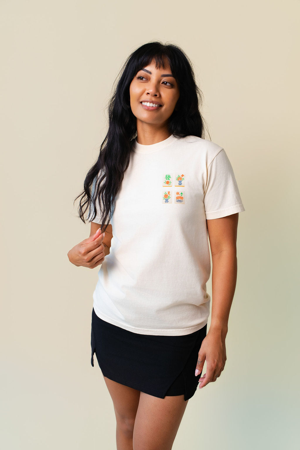 Person wearing a white t-shirt with a small design of mahjong. 