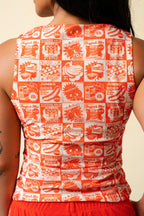 Back of person wearing a tank top with orange vintage-style food coupon pattern and jeans.