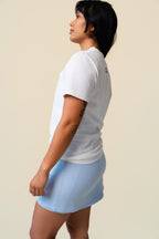 Side of person wearing a white t-shirt with floral designs on a beige background.