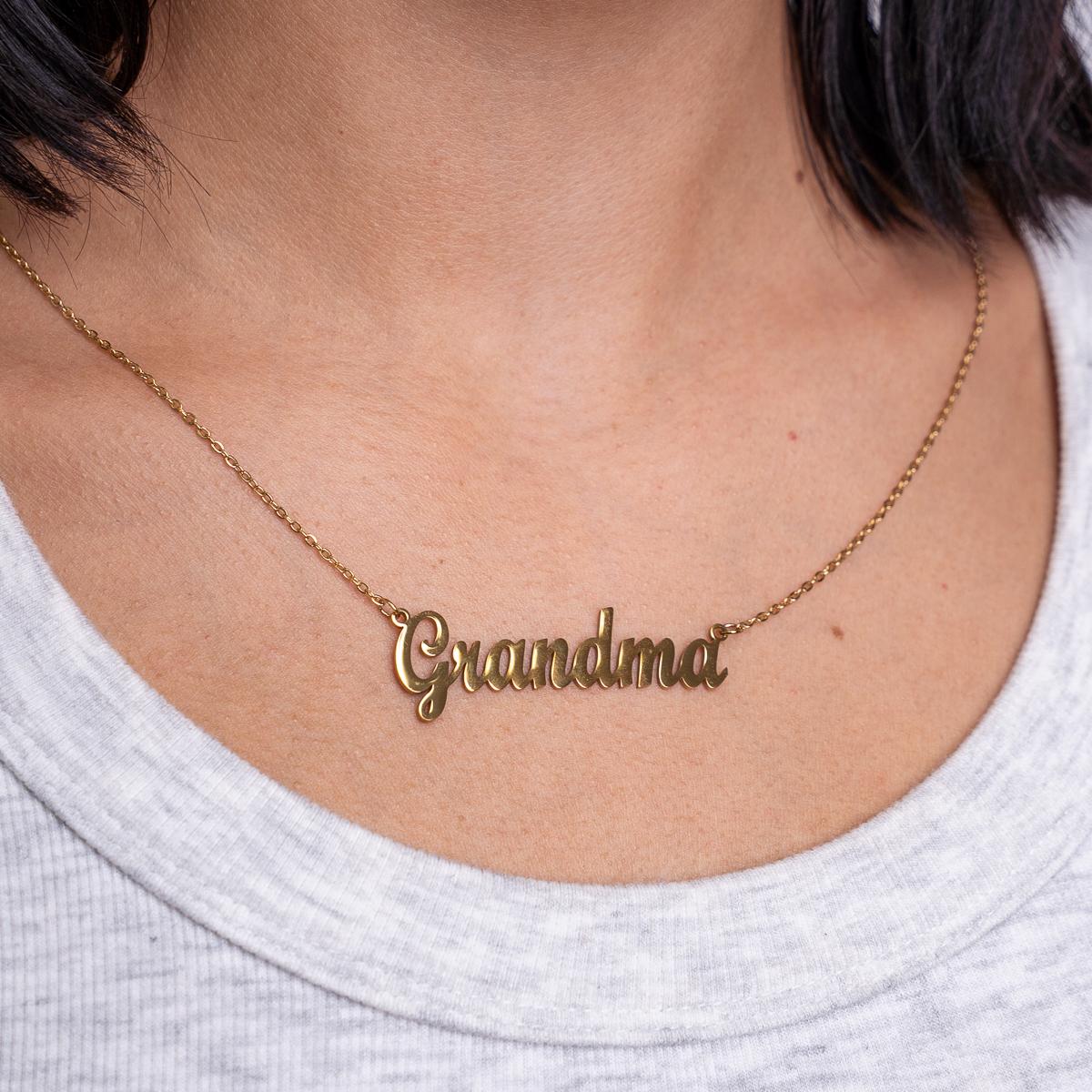 Gold 'Grandma' necklace on a person wearing a light gray shirt.