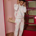 Person wearing a matching patchwork designed outfit in a room with pink walls and a red wardrobe.