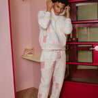 Person wearing a matching patchwork designed outfit in a room with pink walls and a red wardrobe.