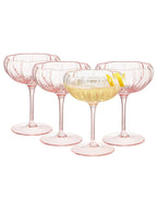 Set of four pink cocktail glasses with a drink inside on a white background