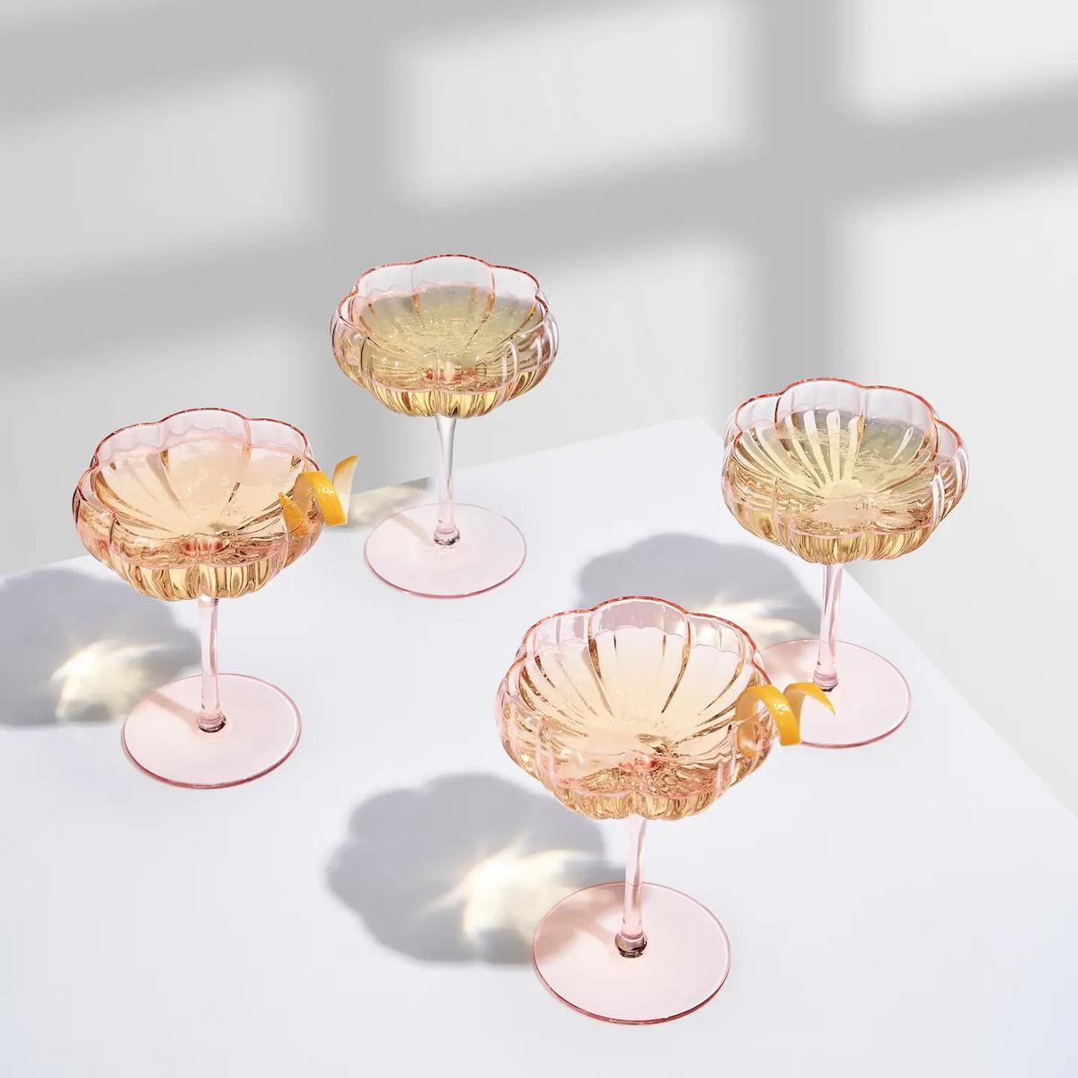 Four pink cocktail glasses with lemon slices on a light background