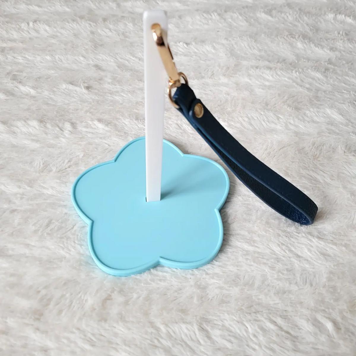 Blue flower-shaped stand with a white yarn spinner and navy blue handle on a light gray background