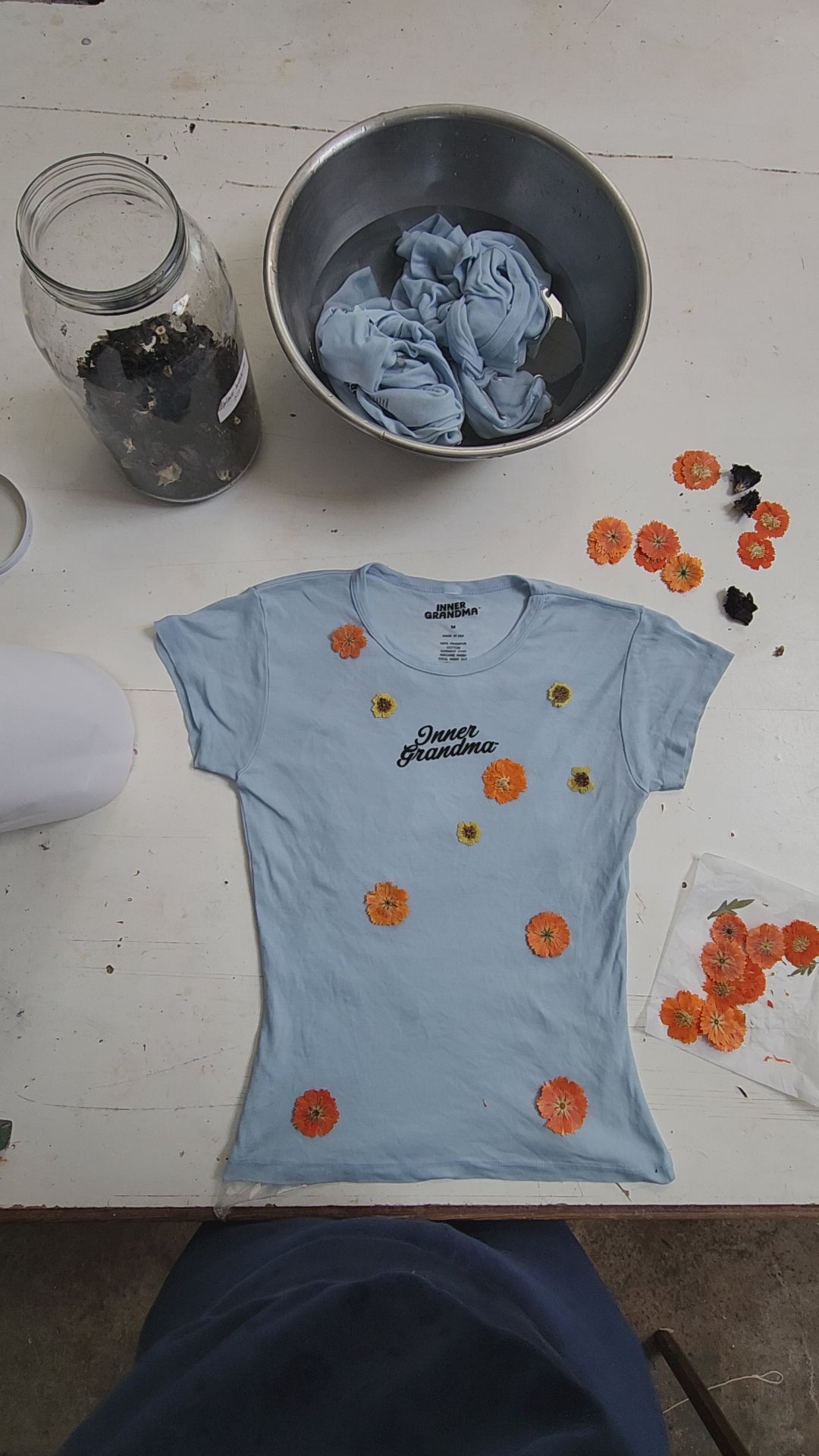 Short-sleeve light blue cropped baby tee shirt with floral pattern naturally dyed by flowers with "Inner Grandma" text