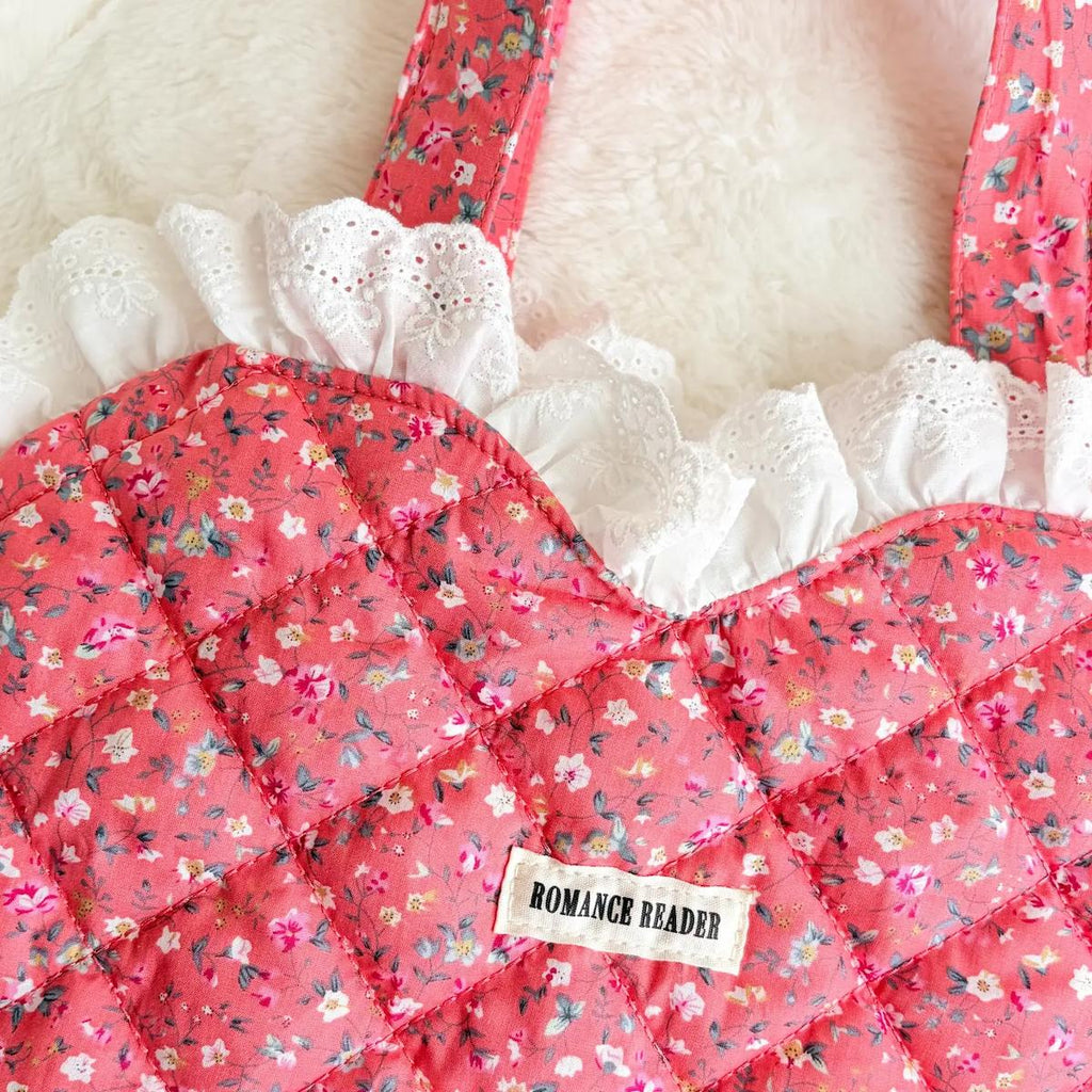 Floral-patterned bag with lace details and a label on a white background