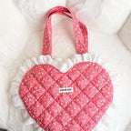 Heart-shaped pink bag with ruffled edge and floral handle on a white background