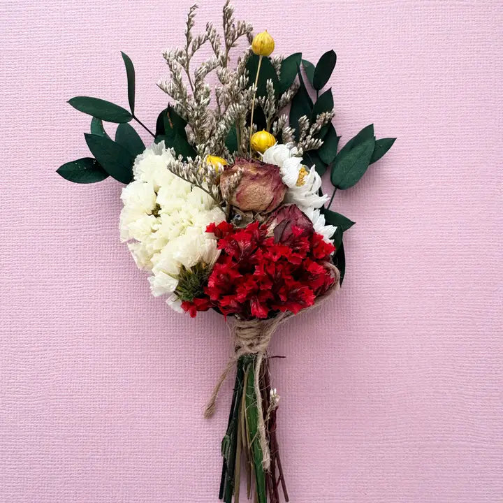 Bouquet of flowers with red, white, and green elements on a pink background