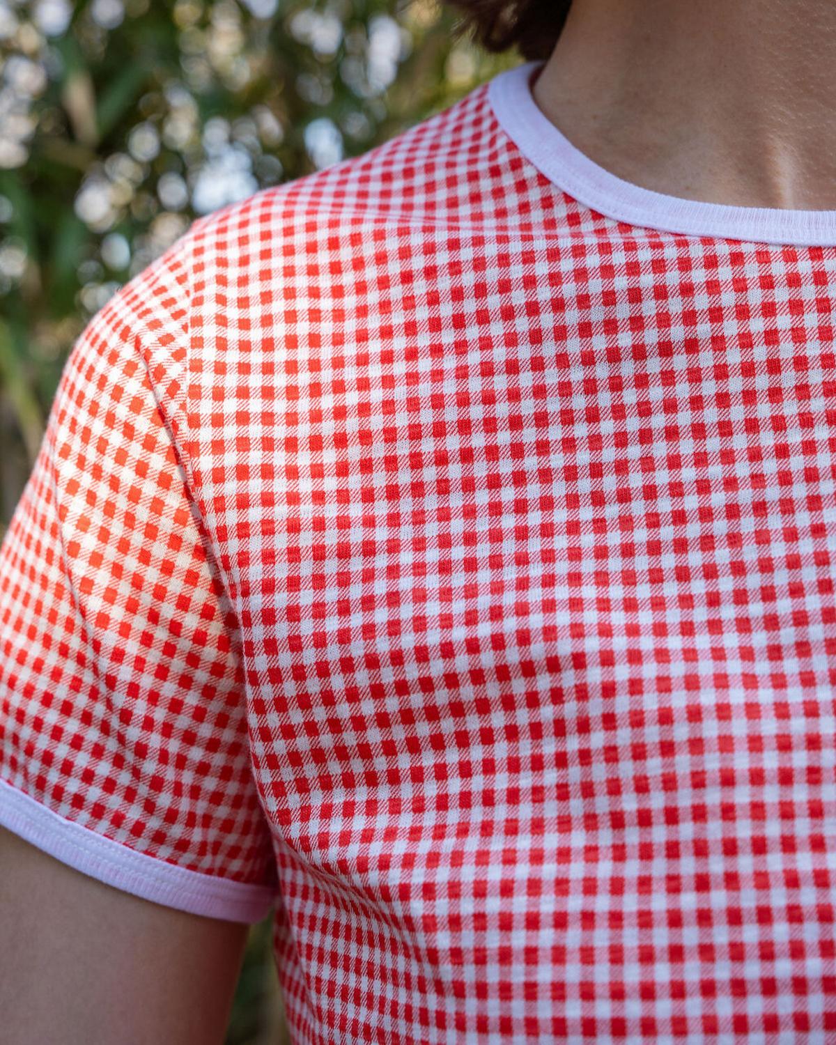 Red and white checkered shirt worn by a person with a blurred natural background
