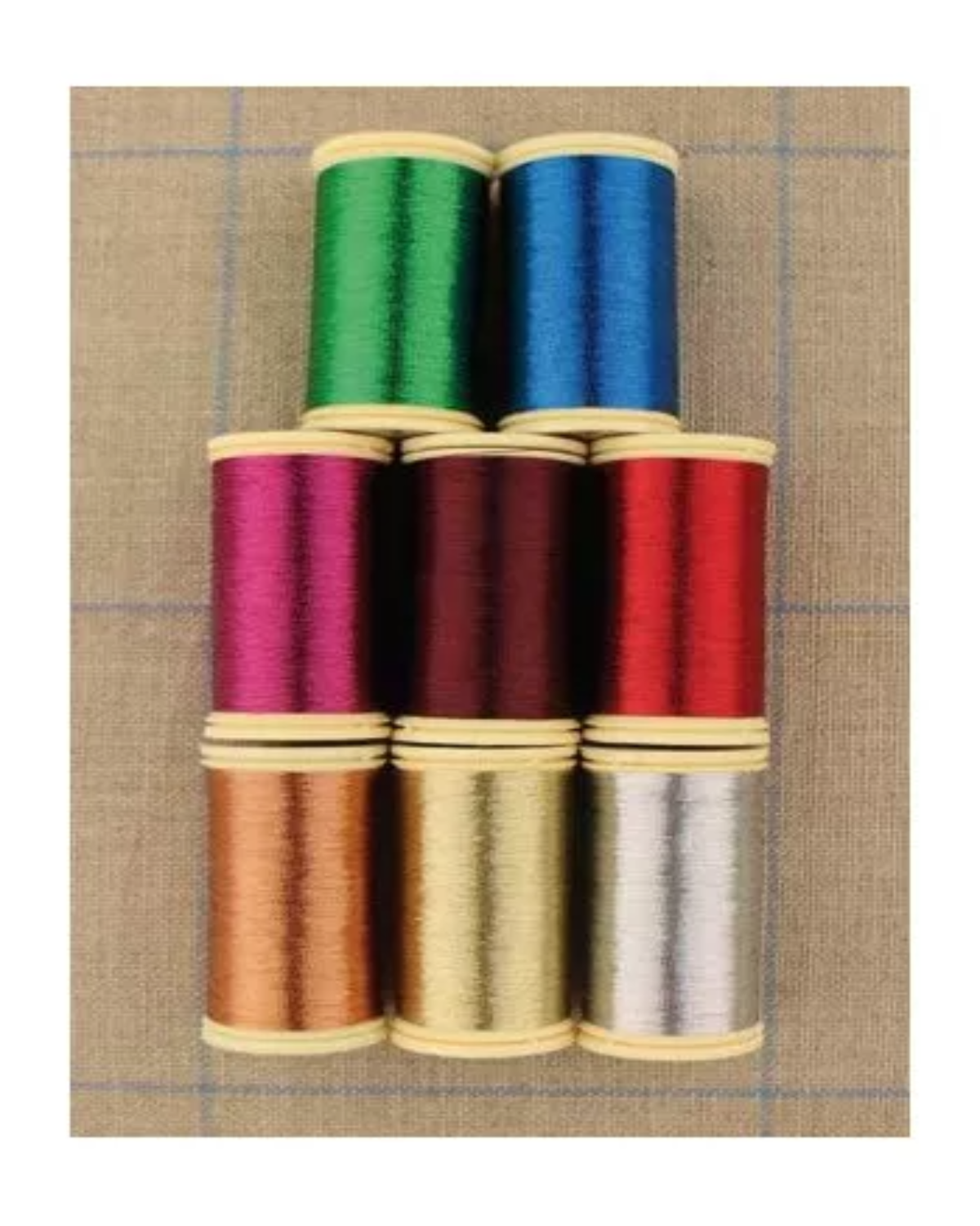 Stack of colorful spools of thread on a textured fabric background
