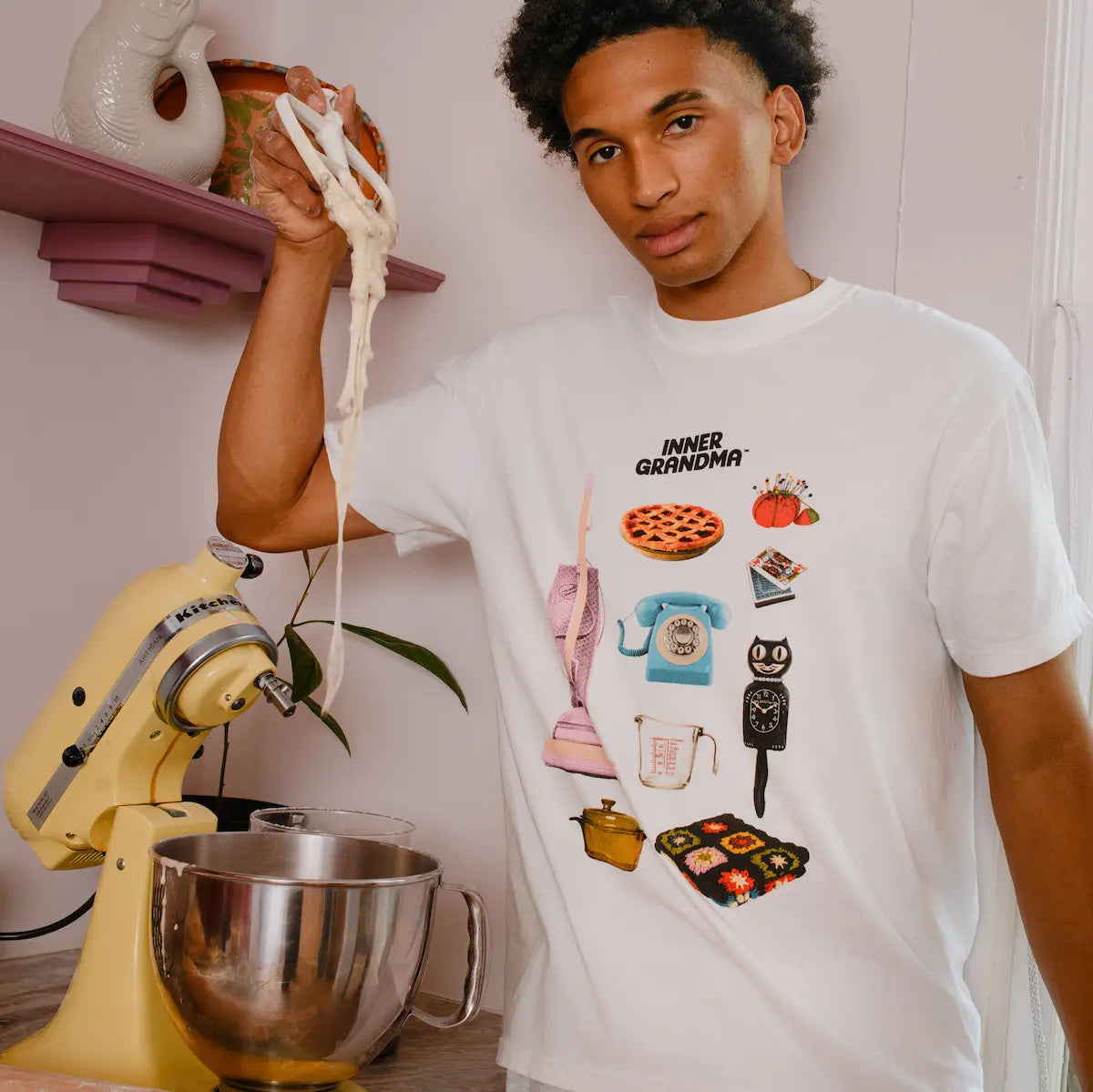 Person wearing a white t-shirt with retro graphic designs in a kitchen setting