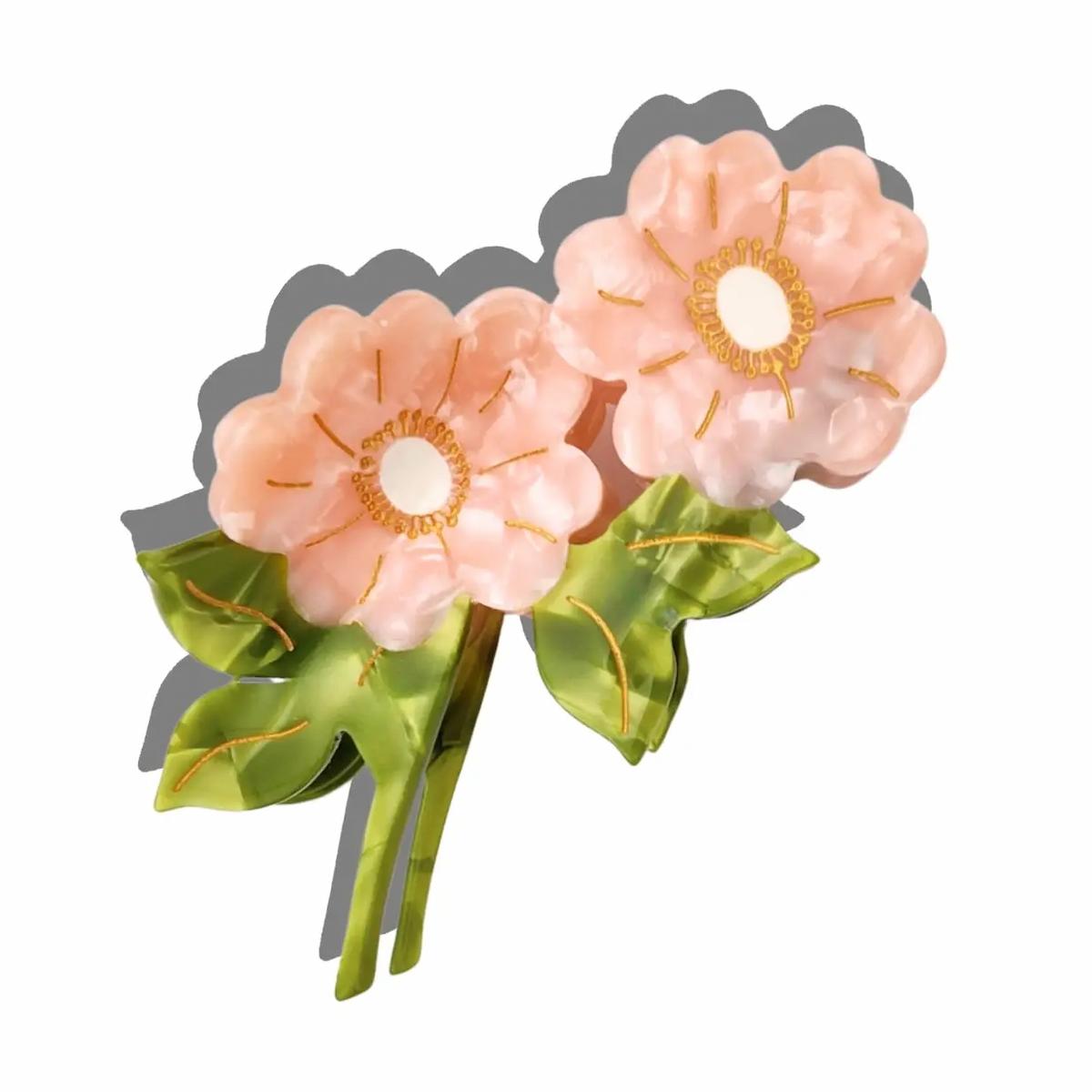 Floral hair clip with pink flowers and green leaves on a white background