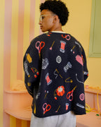 Back of person wearing a colorful sweater with sewing items on it in a pastel-colored room.