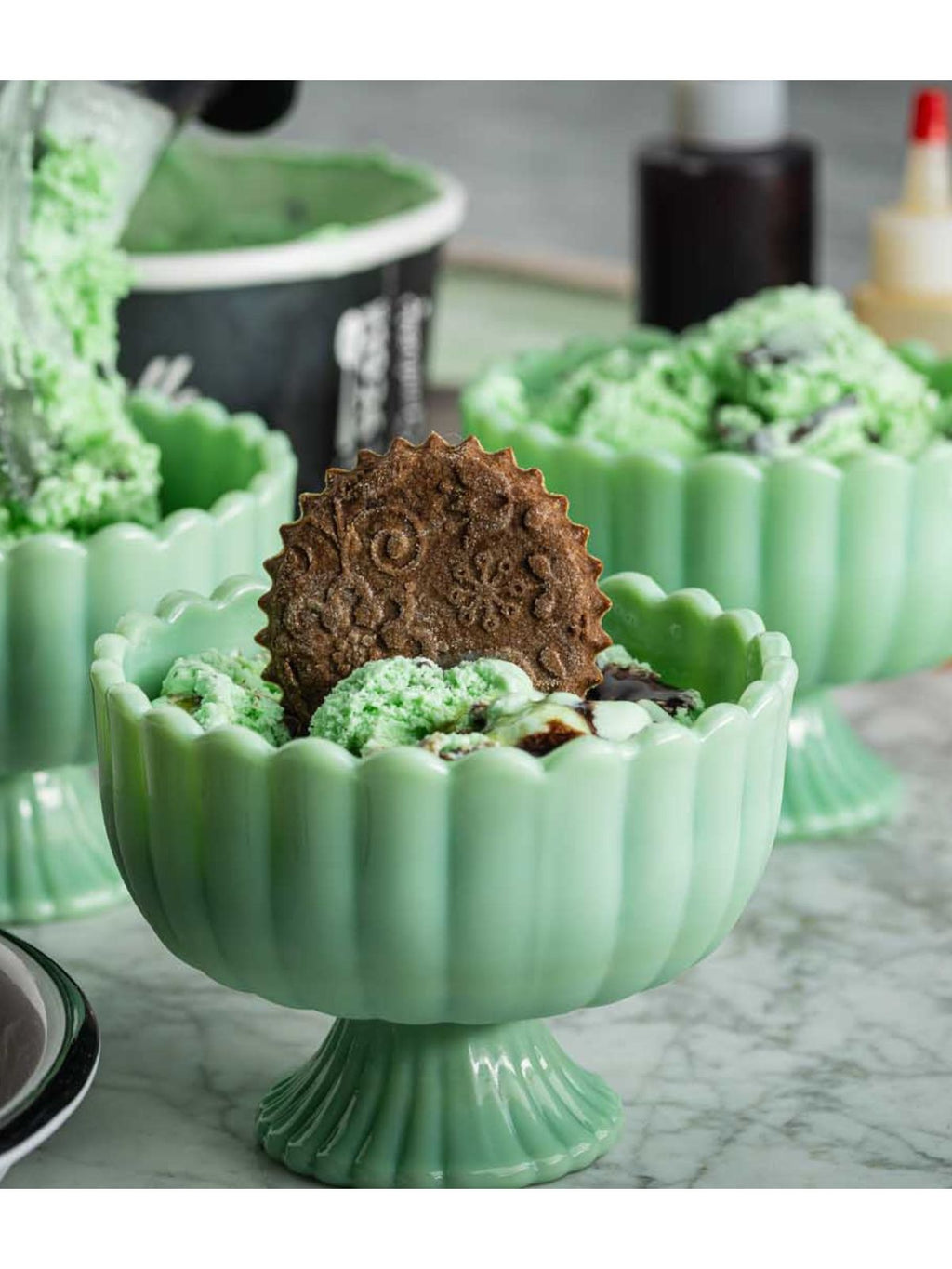 Green ceramic bowl with a decorative cookie on a marble surface