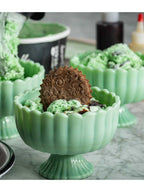 Green ceramic bowl with a decorative cookie on a marble surface