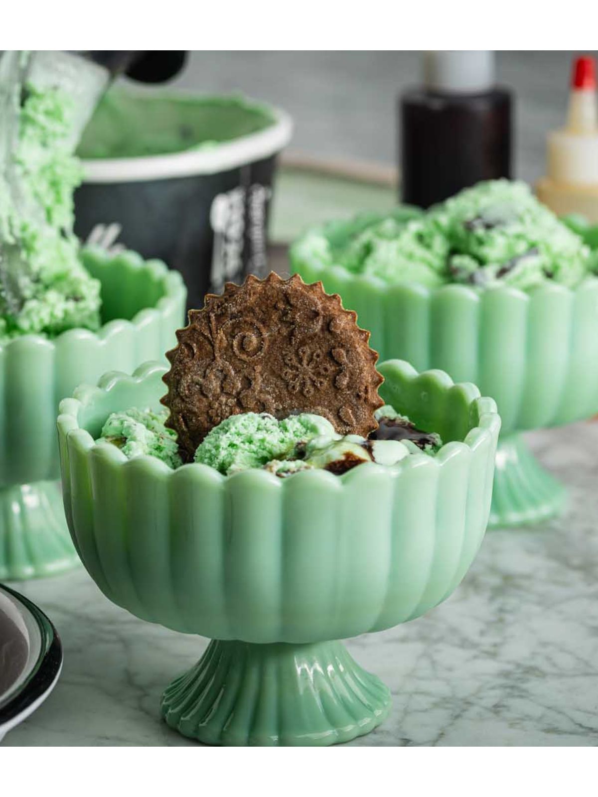 Green ceramic bowl with a decorative cookie on a marble surface