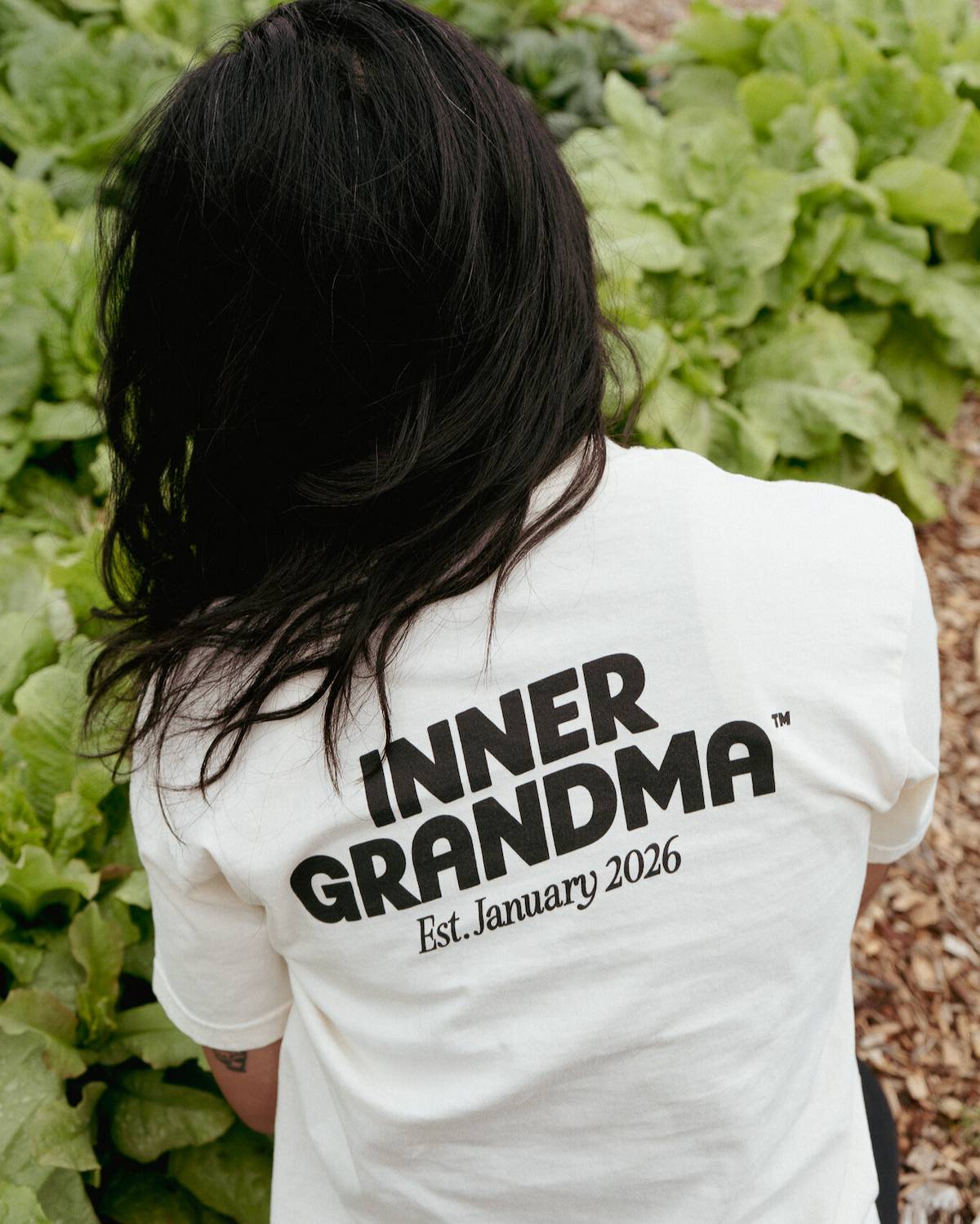Person wearing a white shirt with 'INNER GRANDMA Est. January 2026' text in a garden setting