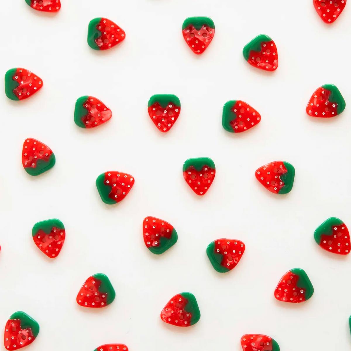 Pattern of red and green strawberry-shaped candies on a white background