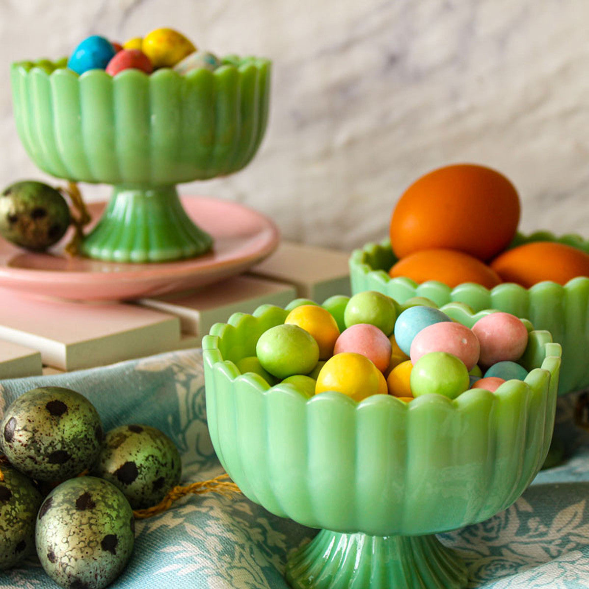 Green glass bowls filled with colorful Easter eggs on a table.