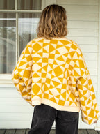 Person wearing a yellow and white geometric patterned sweater outdoors.