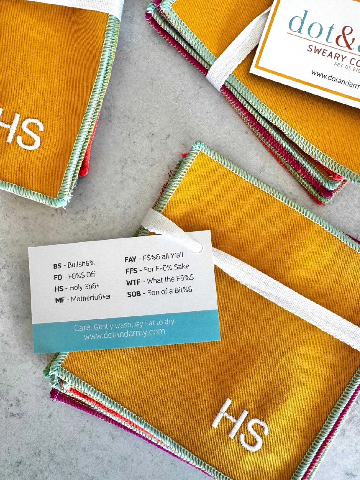 Collection of fabric swatches with 'HS' branding and a business card on a gray surface.