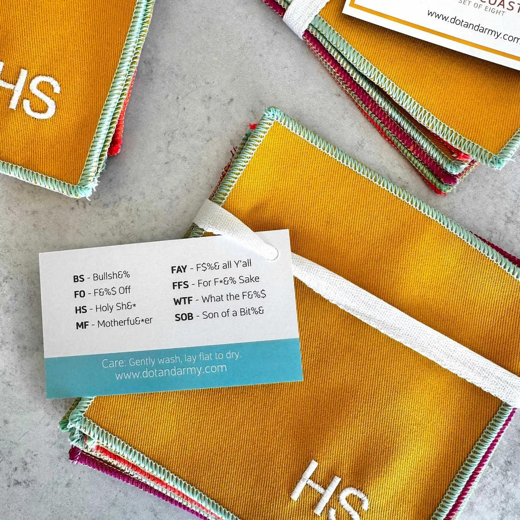 Stack of yellow fabric pads with colorful edges and a tag on a gray surface.