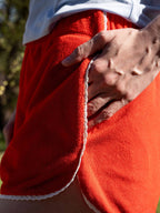 Person wearing red sweatpants with white trim, holding their waist.