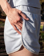 Person wearing light gray shorts with lace trim, standing outdoors.