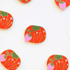 Decorative tomato-shaped pins with floral designs on a white background