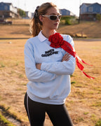 Person wearing a light blue crewneck sweatshirt with a white collar and the words 'INNER GRANDMA' printed in black, accessorized with a large red rose brooch. 