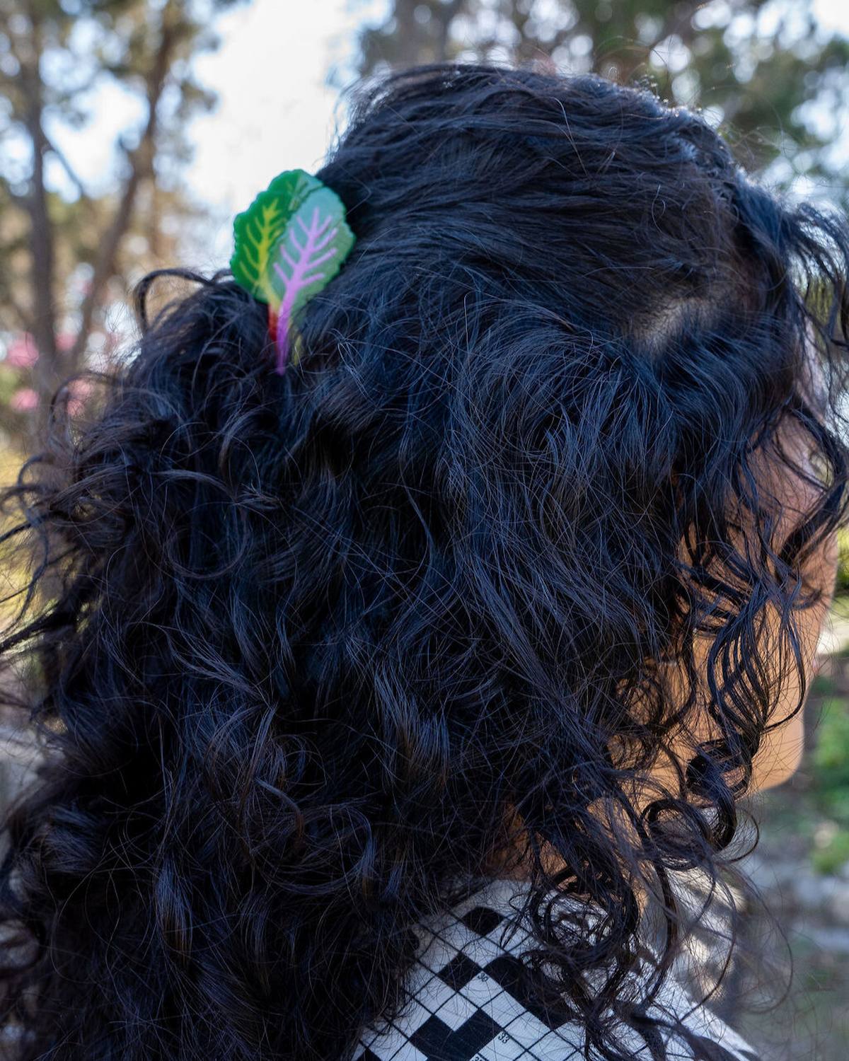 Person with curly hair wearing a green leaf hair accessory outdoors