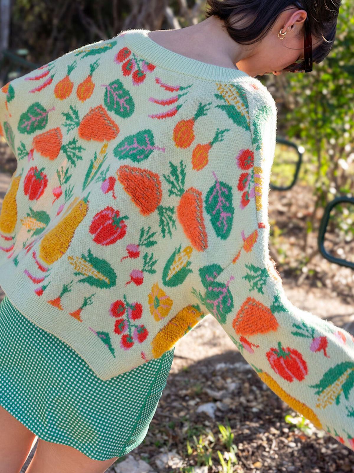 Person wearing a colorful knit cardigan with fruit pattern outdoors