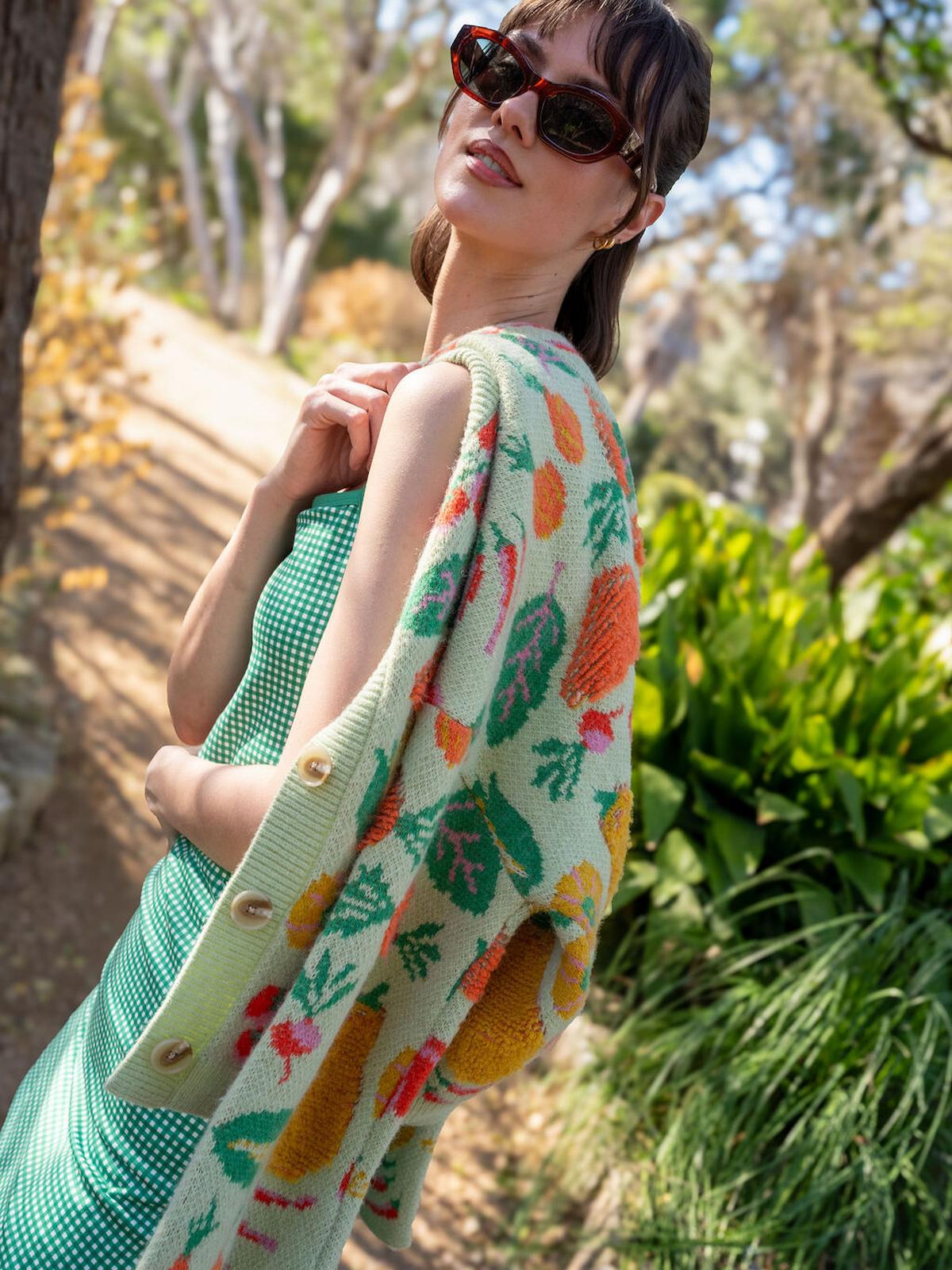 Woman wearing a floral patterned cardigan over a green dress in a natural setting.
